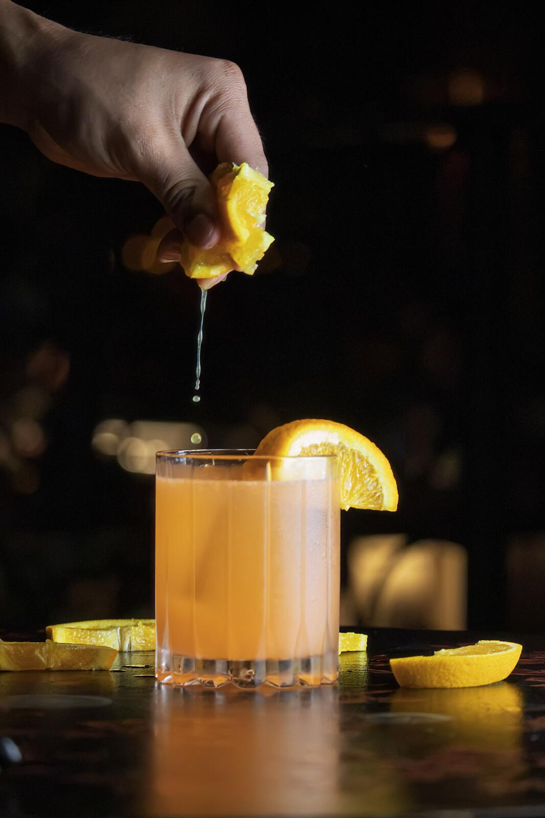 Bartender squeezing an orange over a citrus cocktail at The Betty